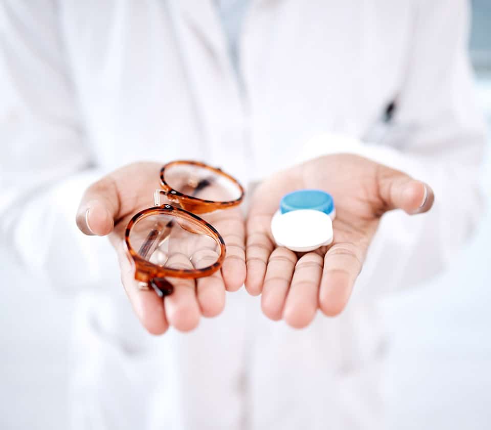 Eye Doctor Holding Eyeglasses and Contact Lenses