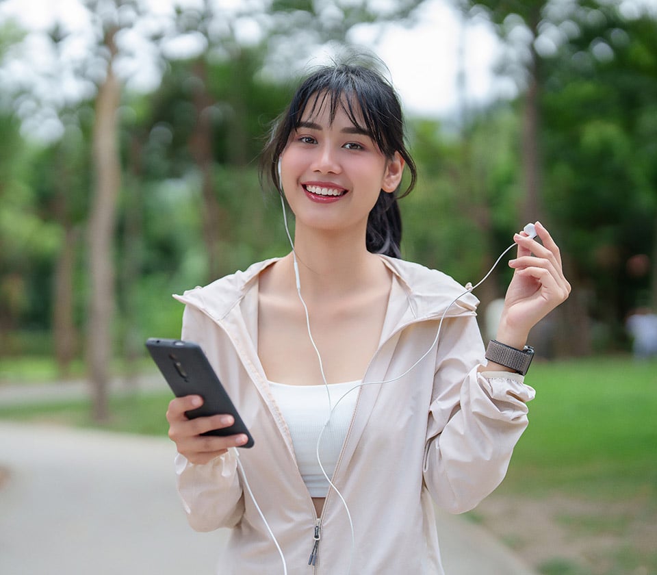 Young woman in a park with phone and headphones